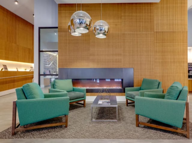 Green armchairs around fireplace and coffee table living room at College and Crown Apartments in New Haven Student Accommodation