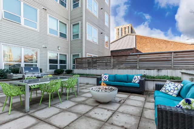 Grill dining table with green chairs fire pit outdoor area at College and Crown Apartments in New Haven Student Accommodation