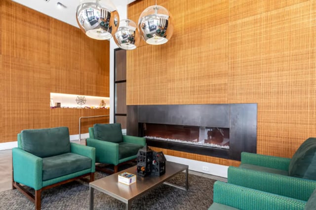 Green armchairs coffee table fireplace living room at College and Crown Apartments in New Haven Student Accommodation