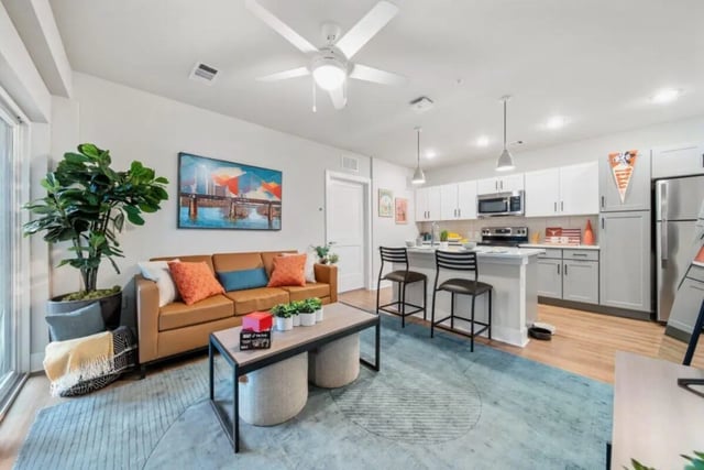 Leather sofa kitchen island and bar stools Living room kitchen at Noble 2500 in Austin Student Accommodation