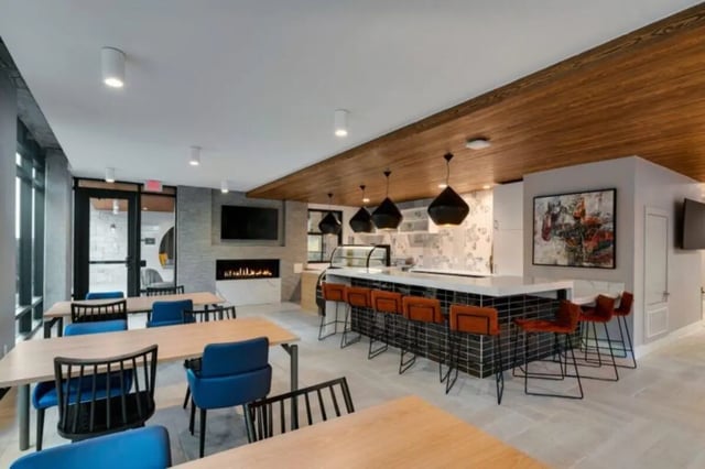 Tables chairs fireplace bar stools communal area at Noble 2500 in Austin Student Accommodation