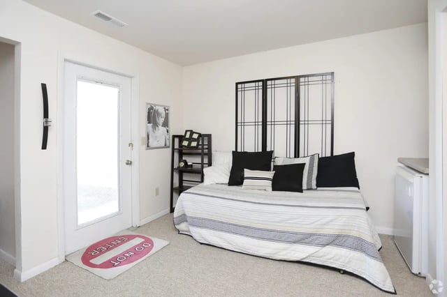 Bed with pillows folding screen and rug bedroom at Campus Communities - College Town Apartments in Big Rapids Student Accommodation