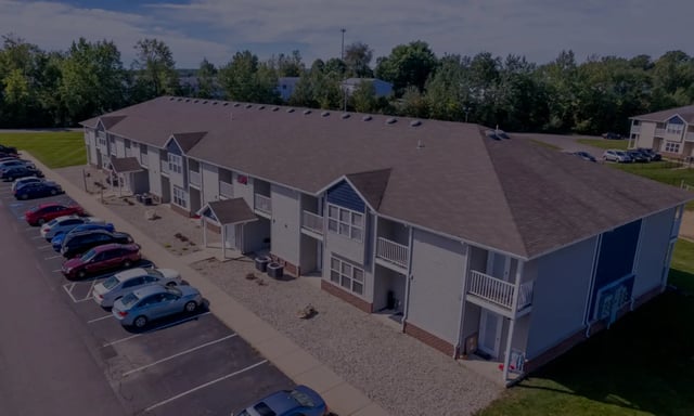 Apartment building parking lot and trees exterior at Campus Communities - College Town Apartments in Big Rapids Student Accommodation