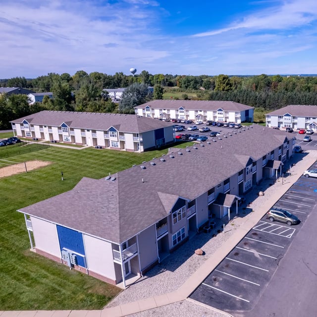 Apartment buildings with parking lot and grass exterior at Campus Communities- Campus Creek Townhomes in Big Rapids Student Accommodation