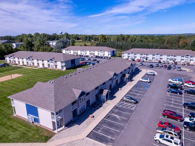 Apartment buildings with parking lots and lawn exterior at Campus Communities- Campus Creek Townhomes in Big Rapids Student Accommodation