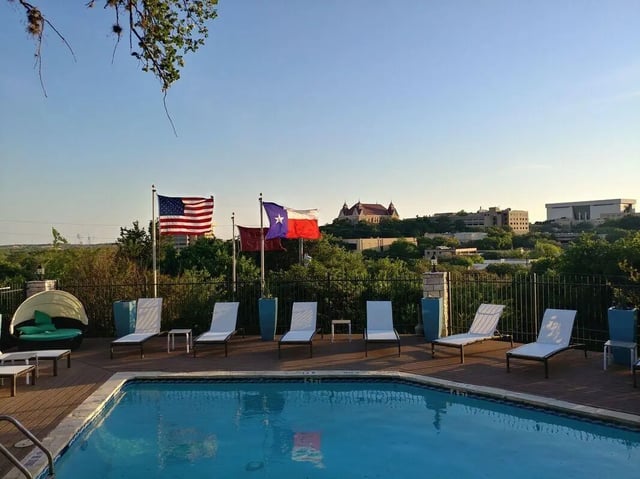 Flags lounge chairs pool and cityscape exterior at The Timbers in San Marcos Student Accommodation