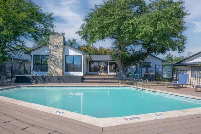 Large swimming pool building and lounge chairs exterior at The Timbers in San Marcos Student Accommodation