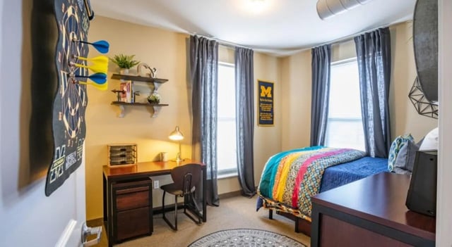 Dartboard desk bed and curtains bedroom at The Courtyards Student Apartments in Ann Arbor Student Accommodation