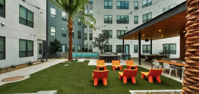 Outdoor seating area with pool and palm tree courtyard at Canvas in Tempe Student Accommodation