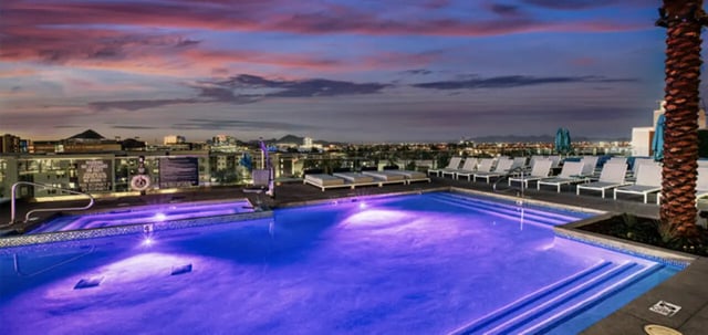 Illuminated pool with lounge chairs and city skyline Exterior at Canvas in Tempe Student Accommodation