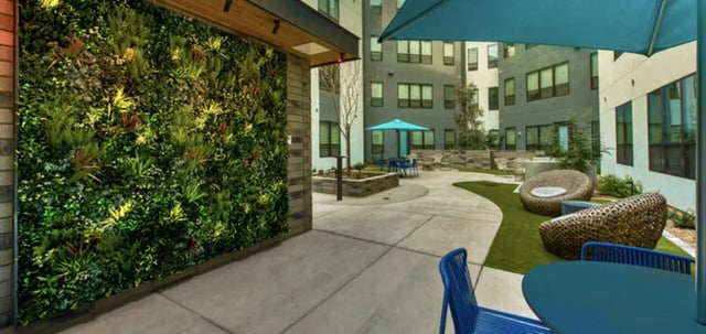 Green living wall lounge chairs and tables exterior at Canvas in Tempe Student Accommodation