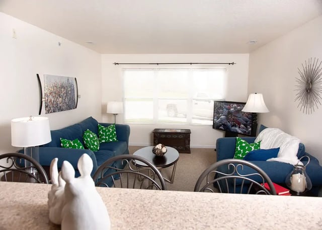 Two blue couches green pillows coffee table living room at Campus Creek Cottages in Big Rapids Student Accommodation