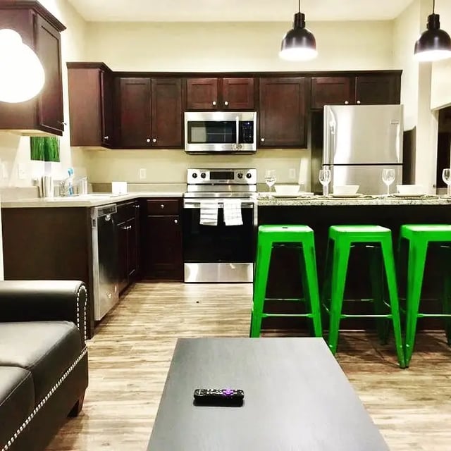 Modern kitchen with dark cabinets and green stools kitchen at Campus Creek Cottages in Big Rapids Student Accommodation