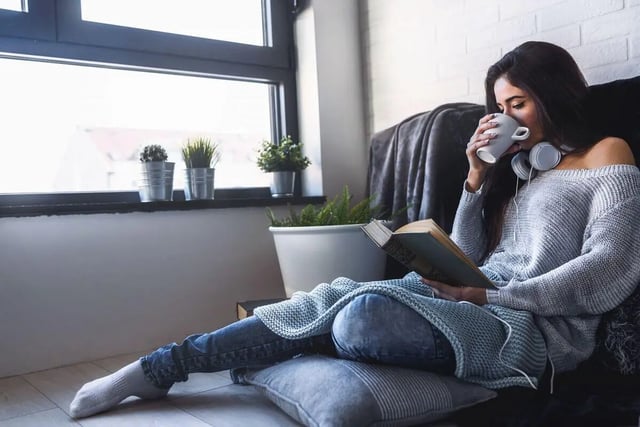 Woman reading drinking coffee comfortable living room at Campus Creek Cottages in Big Rapids Student Accommodation
