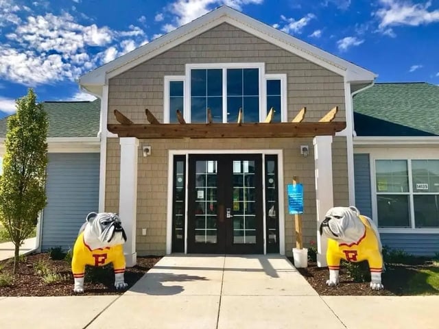 Two bulldog statues flanking building entrance exterior at Campus Creek Cottages in Big Rapids Student Accommodation