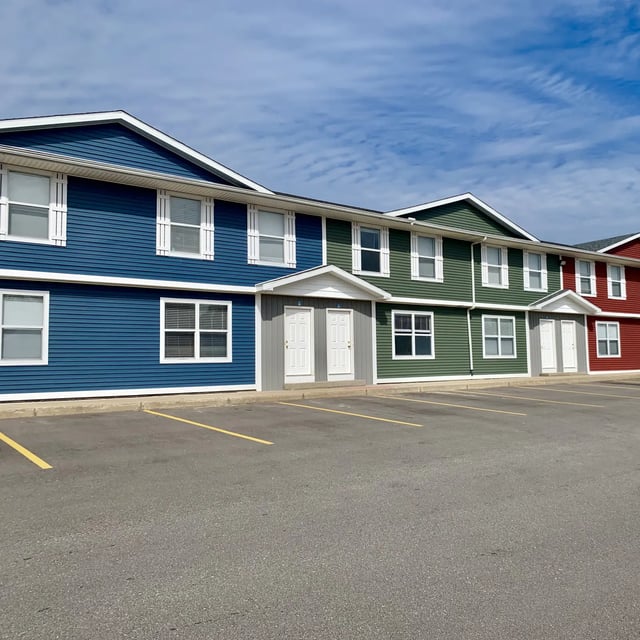 Row of colorful apartments with white shutters and parking exterior at Campus Creek Cottages in Big Rapids Student Accommodation