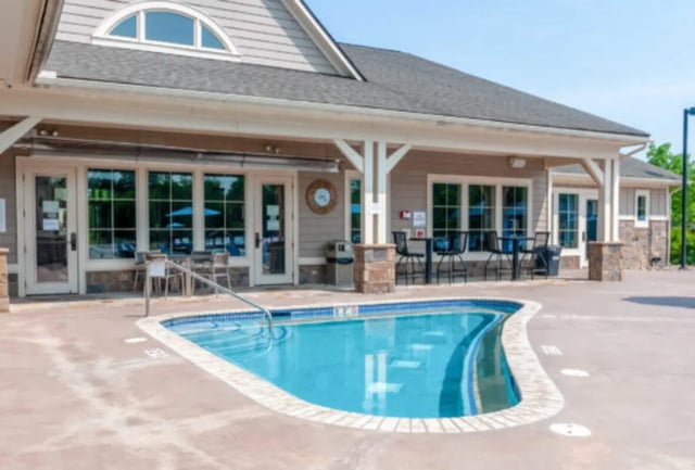 Pool with lounge chairs tables building exterior at Brexx at State College in State College Student Accommodation