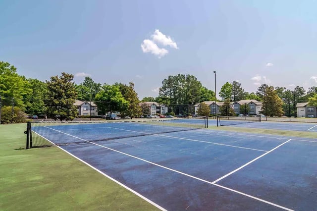 Tennis courts with apartment buildings in background outdoor area at The Townhomes At River Club in Athens Student Accommodation