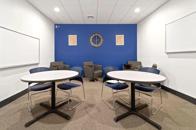 Two tables with chairs and whiteboards common room at The Printing House in Binghamton Student Accommodation