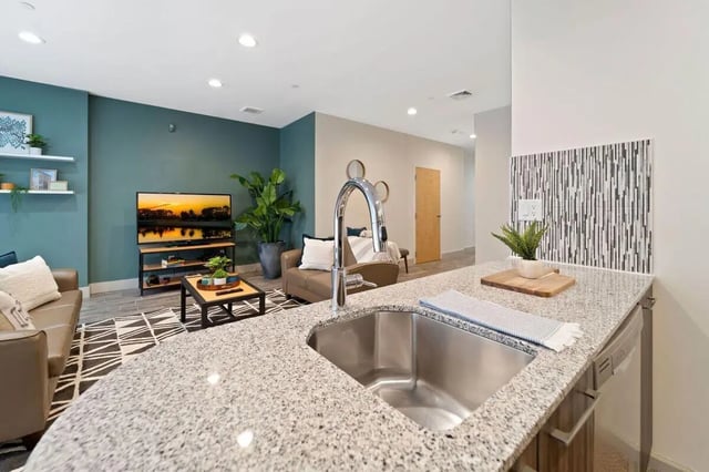 Kitchen sink island granite countertop and living area living room at The Printing House in Binghamton Student Accommodation