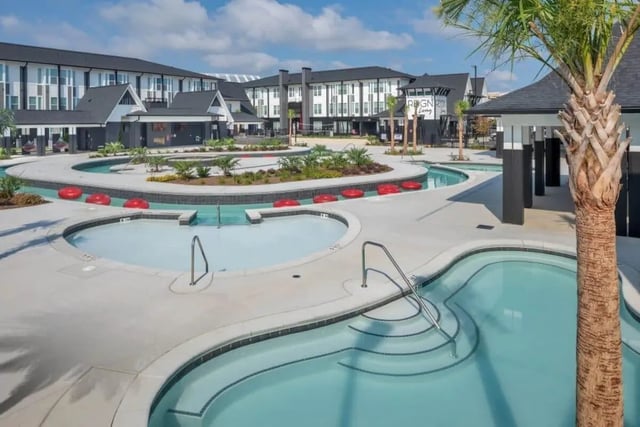 Pools with red floats and palm trees exterior at The Row At The Stadium in Columbia Student Accommodation