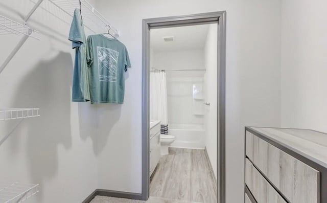 Closet with hanging shirts and bathroom beyond bathroom at The Row At The Stadium in Columbia Student Accommodation