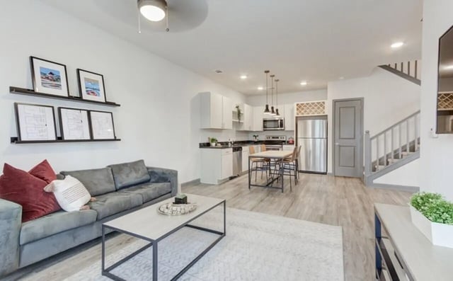 Gray sofa with artwork above and kitchen living area at The Row At The Stadium in Columbia Student Accommodation