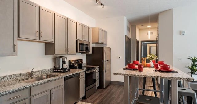 Modern kitchen with gray cabinets dining table and appliances Kitchen at The Flight at Dayton in Dayton Student Accommodation