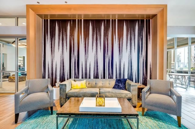 Sofa chairs coffee table with modern art wallpaper living room at The Crossings Apartments in Sacramento Student Accommodation