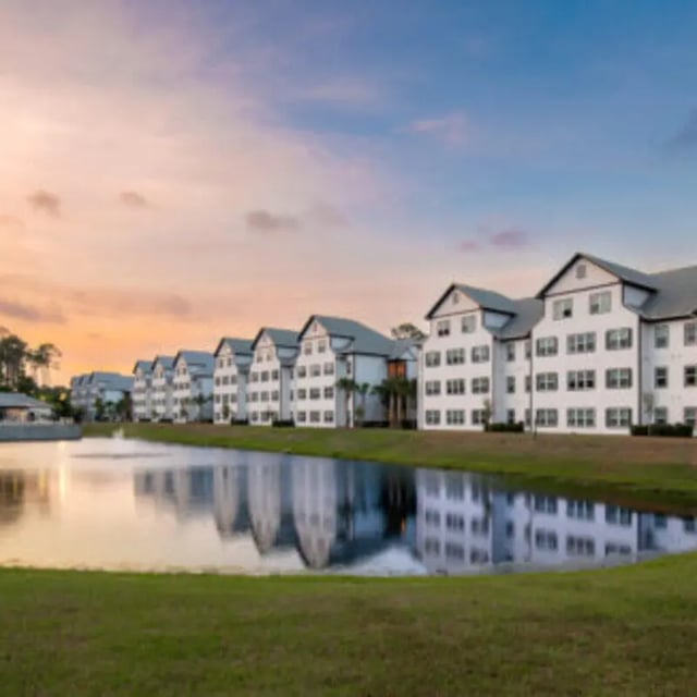 Apartment buildings reflect on lake exterior at Bellamy Daytona in Daytona Beach Student Accommodation