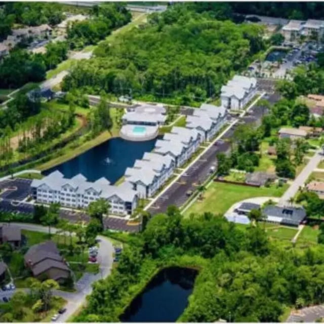 Apartment buildings with pool and lake exterior at Bellamy Daytona in Daytona Beach Student Accommodation