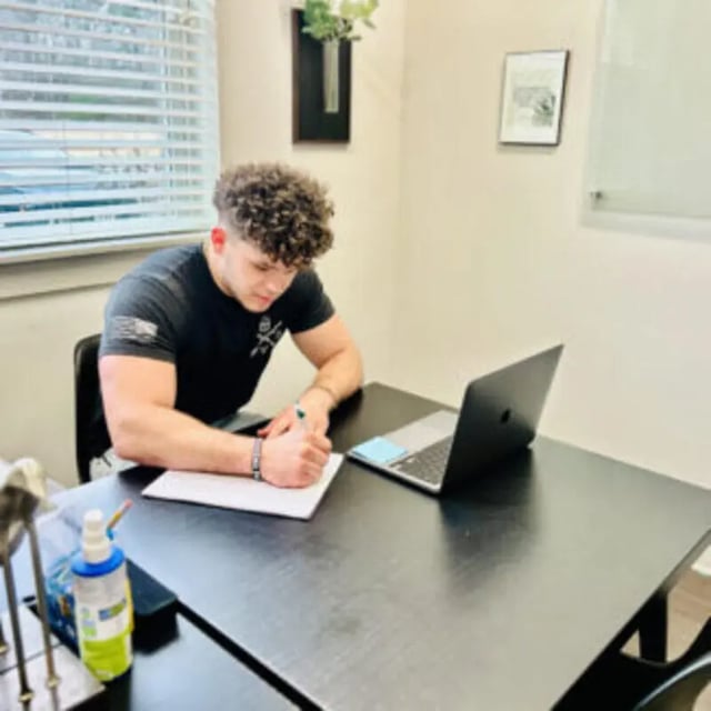 Man writing at desk with laptop study area at Bellamy Florence in Florence Student Accommodation