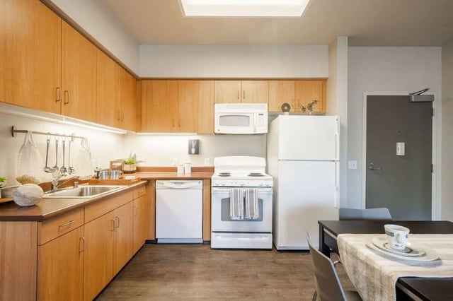 Wooden cabinets sink stove refrigerator microwave kitchen at Claremont Collegiate Apartments