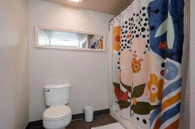 Toilet white bin patterned shower curtain bathroom at Claremont Collegiate Apartments