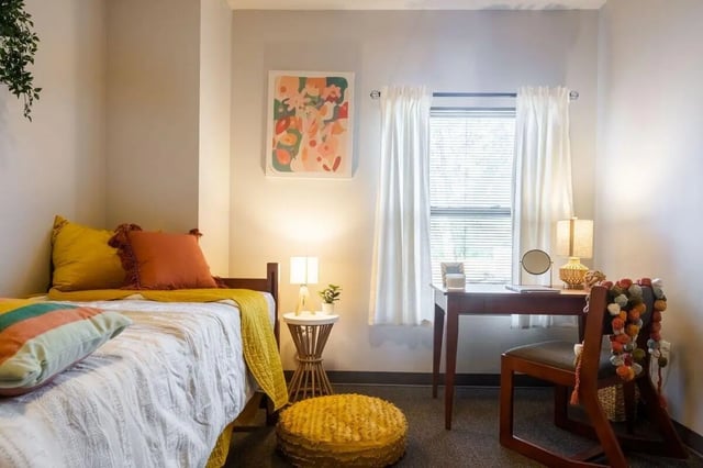Bed desk lamp artwork pillows stool bedroom study area at Claremont Collegiate Apartments