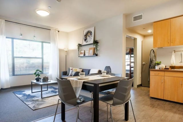 Dining table with chairs sofa and kitchen living area at Claremont Collegiate Apartments