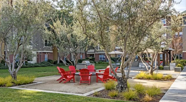 Red chairs around fire pit with building exterior at The U Apartments in Davis Student Accommodation