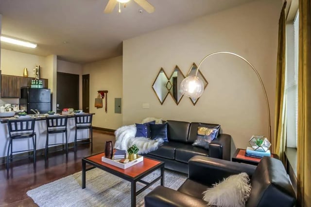 Black leather sofas coffee table kitchen living area at Crimson in Tuscaloosa Student Accommodation