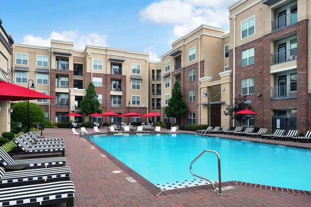 Apartment buildings surrounding large blue pool with lounge chairs exterior at Crimson in Tuscaloosa Student Accommodation