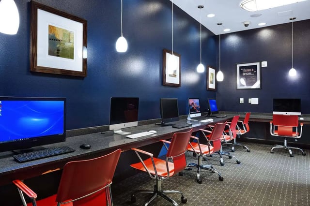Computers with red chairs and artwork study area at Crimson in Tuscaloosa Student Accommodation
