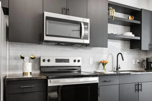 Modern kitchen with dark cabinets stove microwave and sink kitchen at UNITi Bishop Arts in Dallas Student Accommodation
