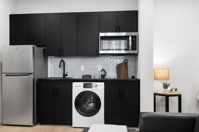 Refrigerator microwave washer black cabinets kitchen area at UNITi Bishop Arts in Dallas Student Accommodation