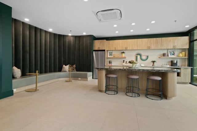 Curved green sofa with bar stools kitchen area at UNITi Bishop Arts in Dallas Student Accommodation