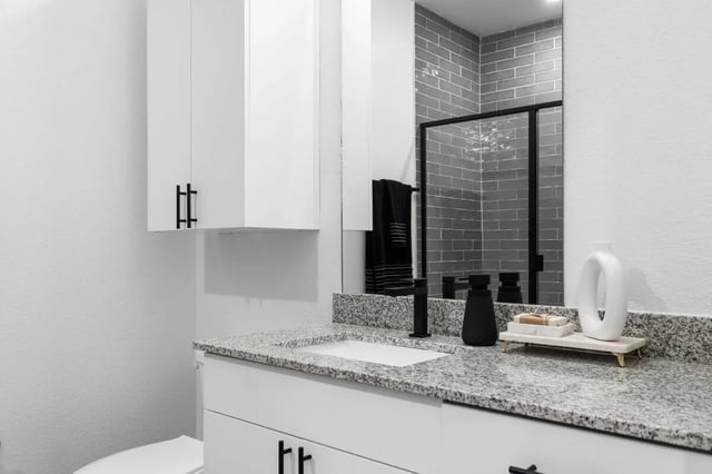 White vanity grey tiled shower white cabinets bathroom at UNITi Bishop Arts in Dallas Student Accommodation