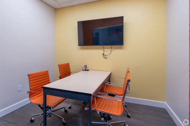 Table and orange chairs with wall mounted TV meeting room at Clemson Edge in Clemson Student Accommodation