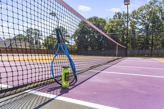 Tennis rackets and balls next to net tennis court at Clemson Edge in Clemson Student Accommodation