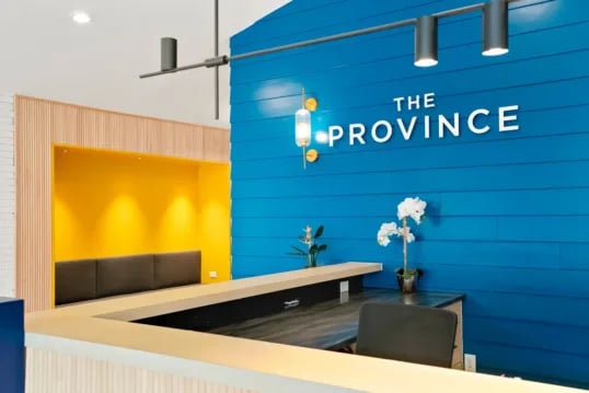Reception desk with bright blue wall and logo at The Province Boulder in Boulder Student Accommodation