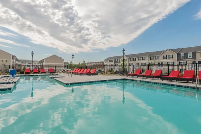 Pool with red loungers and apartment buildings exterior at Copper Beech at Ames Apartments in Ames Student Accommodation
