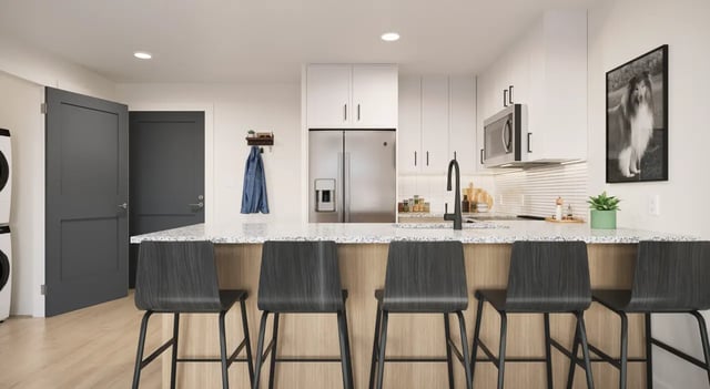 Kitchen with granite island modern cabinets refrigerator and chairs kitchen at Aspire Reserve in College Station Student Accommodation