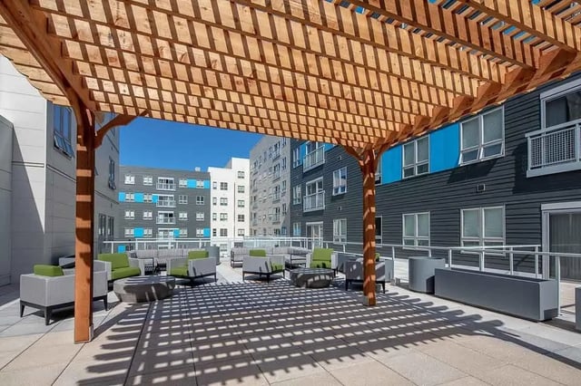 Outdoor seating under a pergola and apartment buildings exterior at Theory Syracuse in Syracuse Student Accommodation